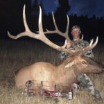 A man poses with the elk he got at Elk Ridge Outfitters